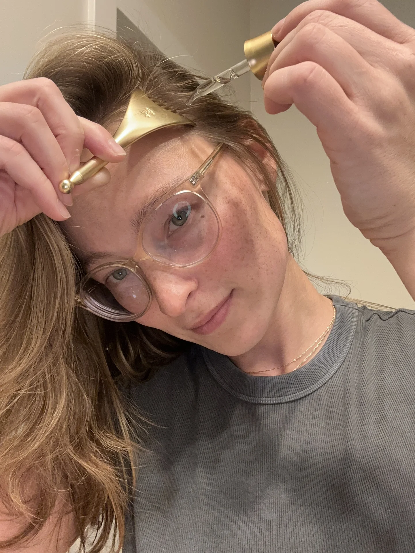 Nicole applying RE:YOU serum along her hair part with the dropper