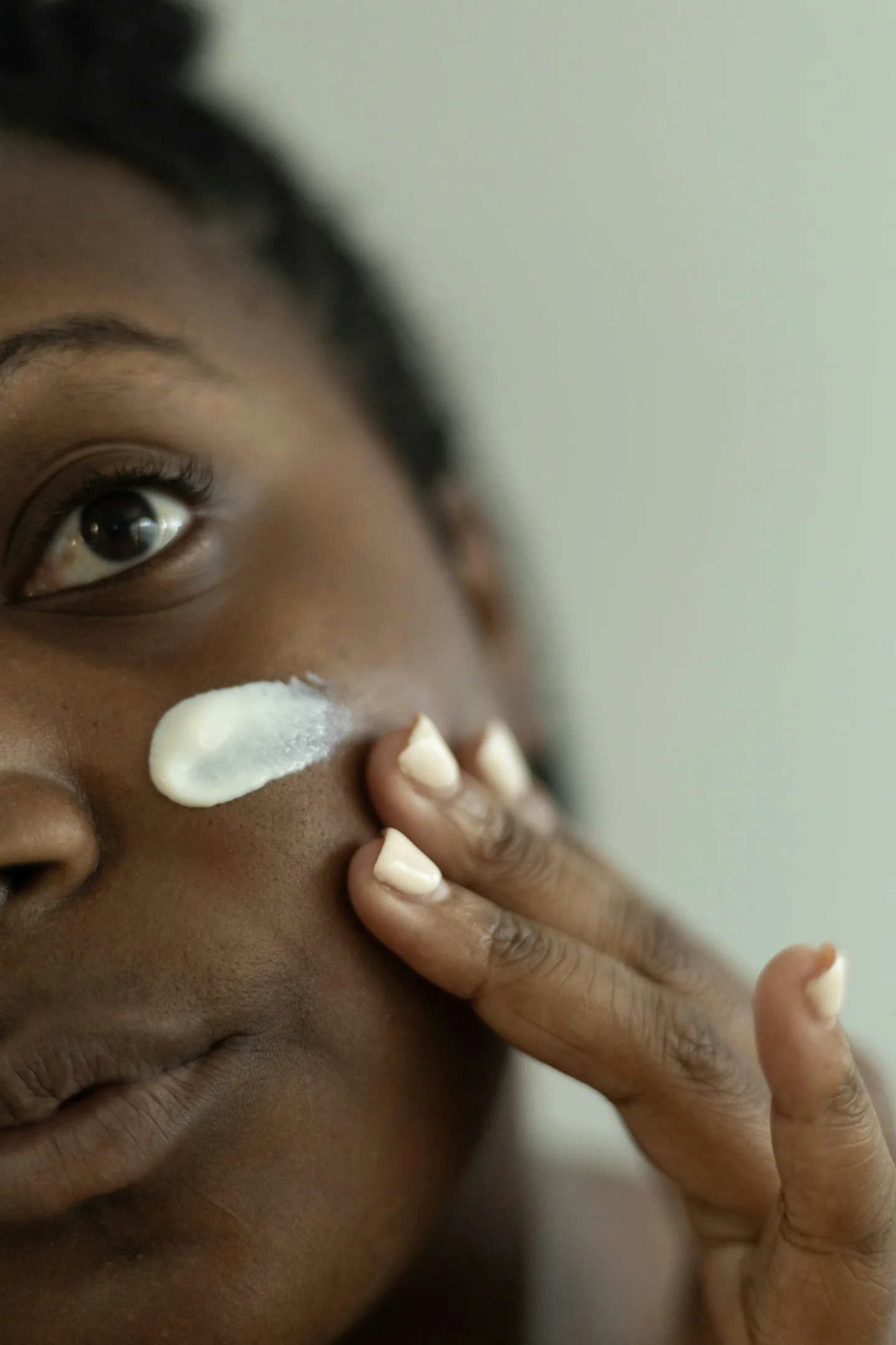 Close view of a woman applying cream to her cheek