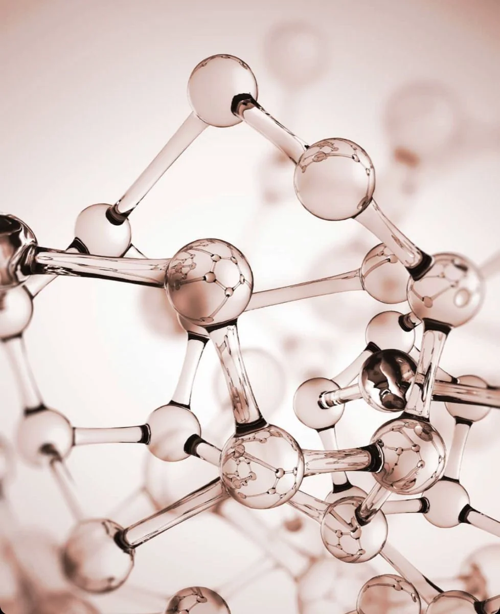 Rose-gold molecular model photographed against a soft pink background