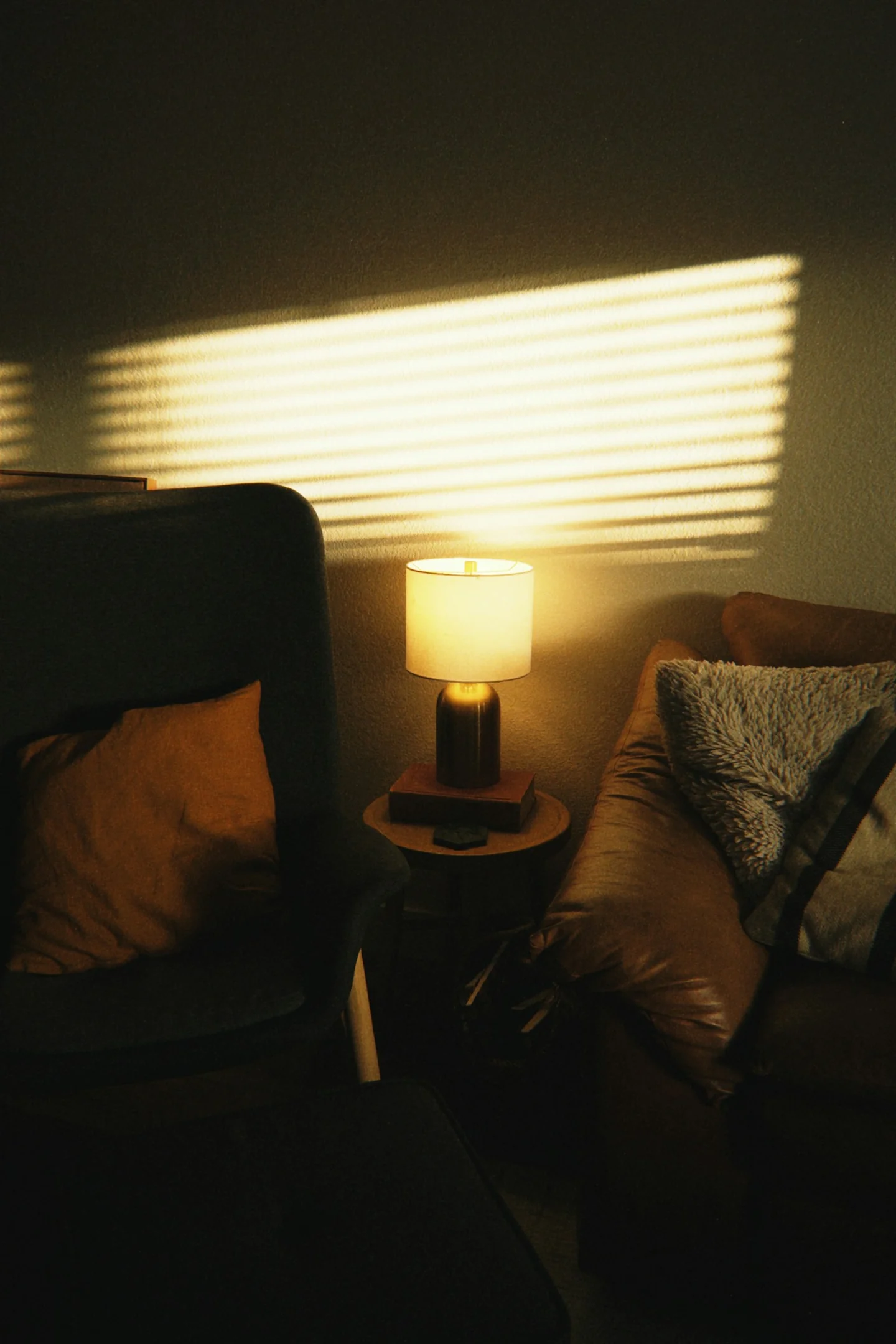 A lit table lamp beside an armchair in a living room