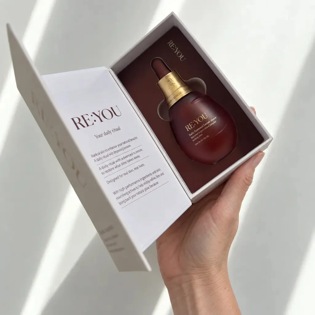 RE:YOU serum bottle in its open presentation box, held in a hand