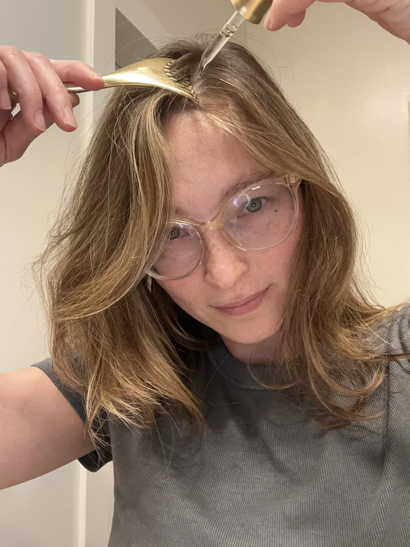 Nicole using a scalp tool to part her hair while applying the serum