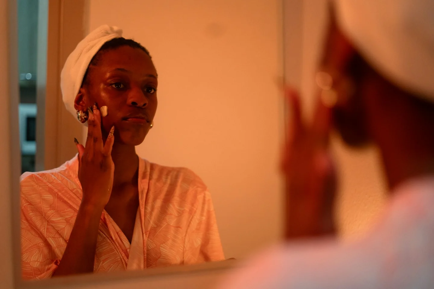A woman applying skincare while looking into a mirror
