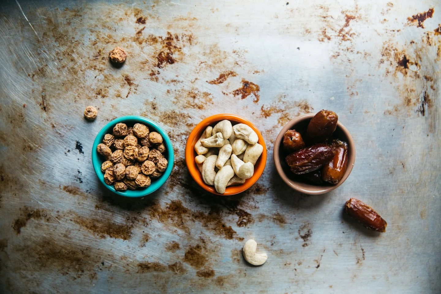 Three bowls containing nuts and dried fruit